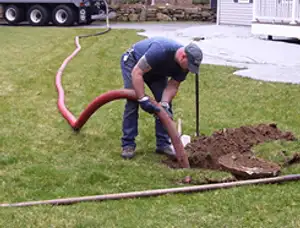 Septic pumping technician servicing a residential septic tank with a vacuum hose in Lakeland, FL