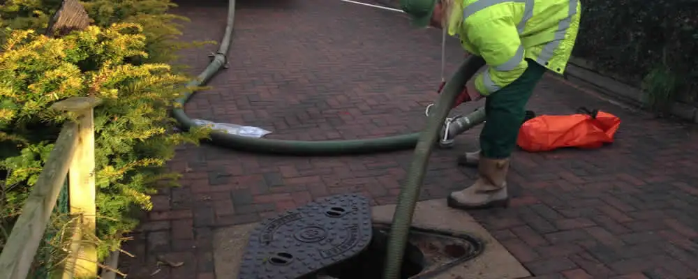 Septic tank cleaning technician servicing a septic tank with a vacuum hose in Lakeland, FL