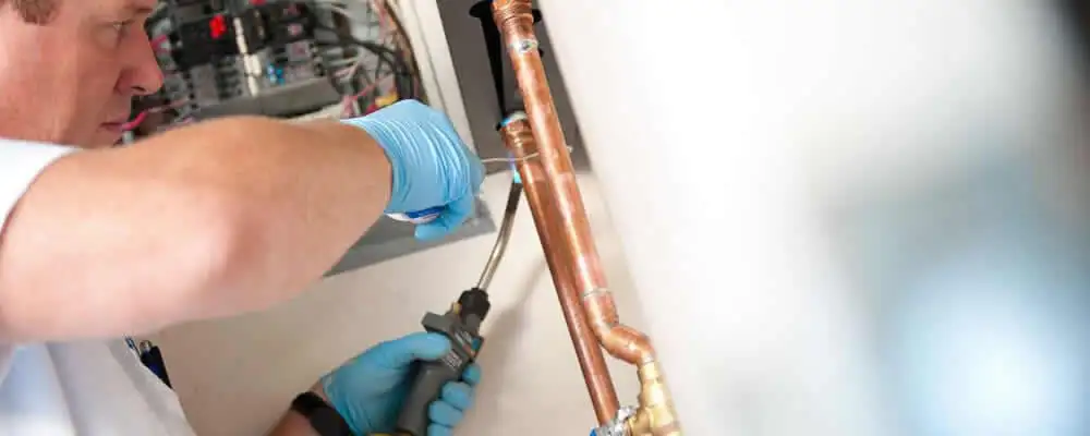 Water heater repair technician testing copper pipe connections and controls in Lakeland, FL